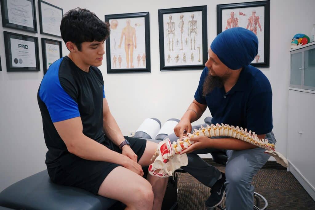 Chiropractic provider using a spine model to explain spinal anatomy and chiropractic care to a patient in Goldsboro, NC.