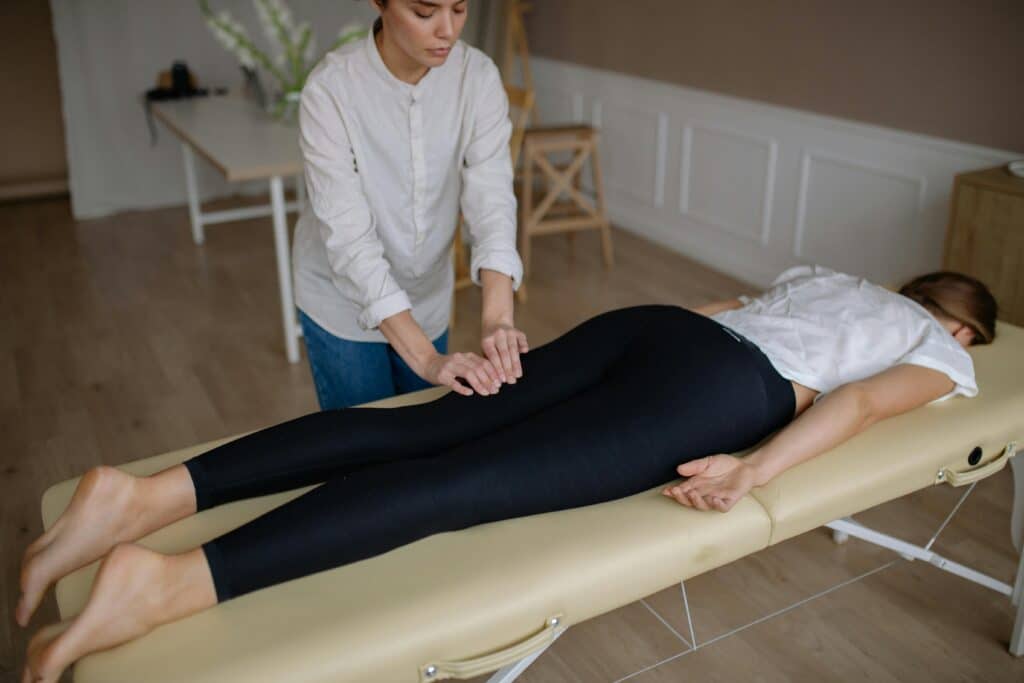 Chiropractic provider assessing a patient’s hip and lower back area during a spinal and joint mobility evaluation in Goldsboro, NC.